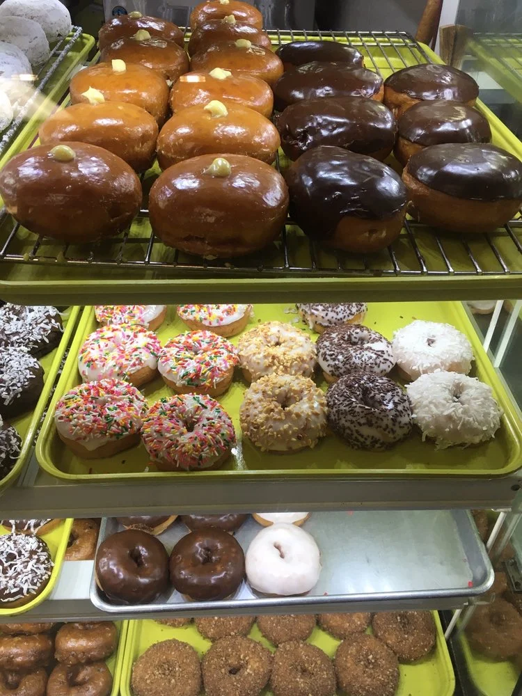 Rows of glazed and frosted donuts in the case